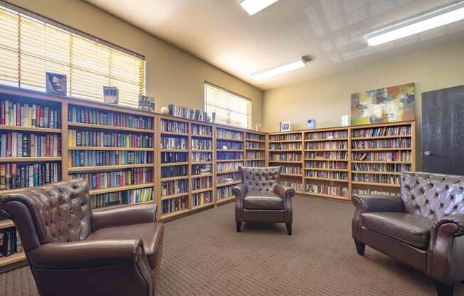 a library with brown leather chairs and bookshelves