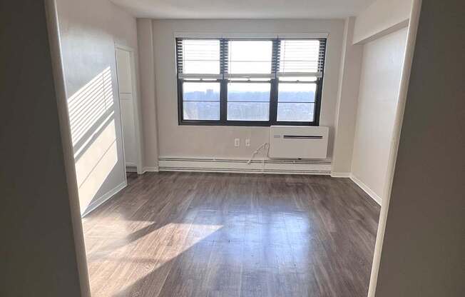 A room with a window and wooden flooring.