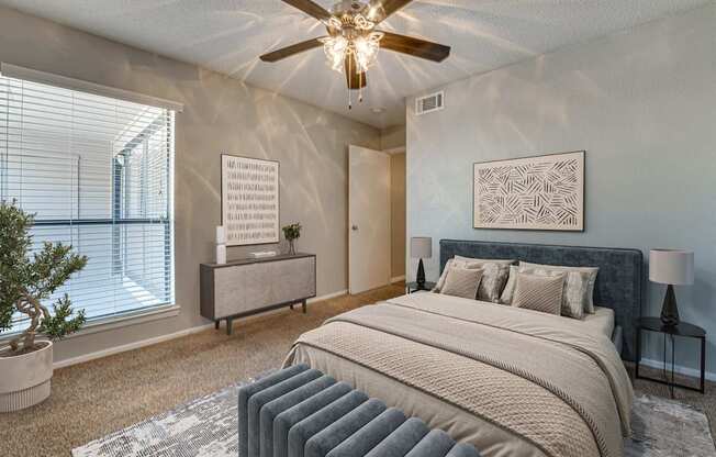 A bedroom with a large bed and a ceiling fan.