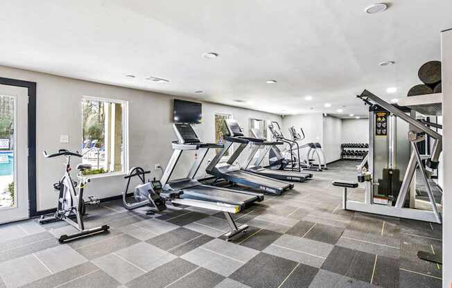 A spacious gym with treadmills, elliptical machines, and a stationary bike.