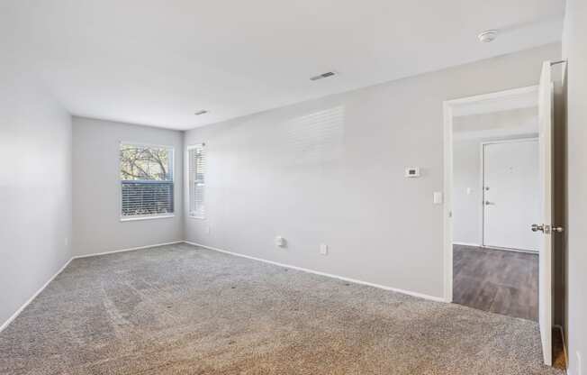 A spacious room with a carpeted floor and a door on the right side.