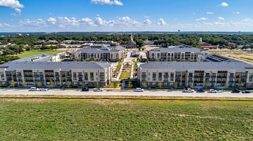 A large, modern building complex with a parking lot in front.