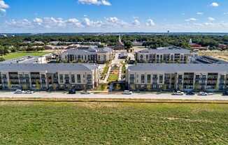 A large, modern building complex with a parking lot in front.