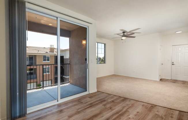 an empty living room with a large window and a ceiling fan