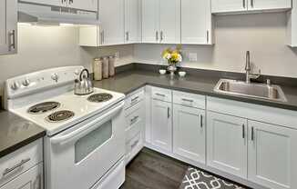 a kitchen with white cabinets and a white stove and sink at Quartz Creek, Mountlake Terrace