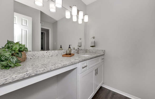 A bathroom with a marble countertop and white cabinets.