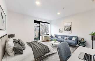 A modern bedroom with a large bed and a laptop on the desk.