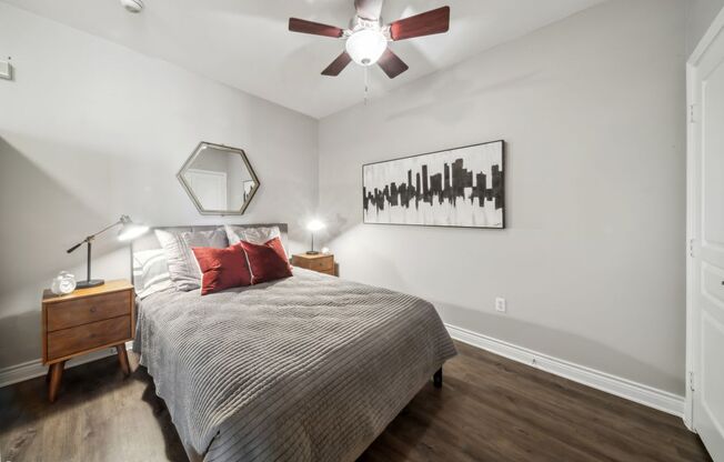 A bedroom with a bed, nightstand, and a painting on the wall.