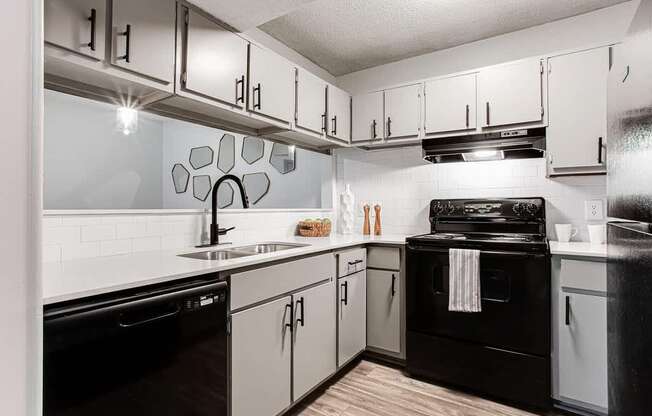 A modern kitchen with black appliances and white cabinets.