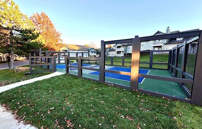 a fenced in area with a trampoline on the grass