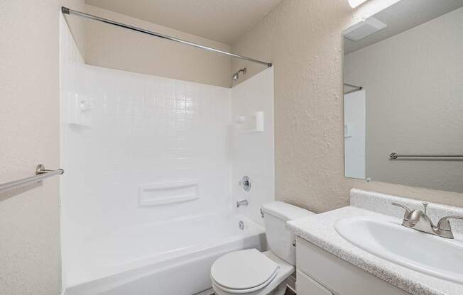 Clean bathroom with a standard toilet, sink, and white finishes in a Peak 88 Apartment home in Renton, WA.