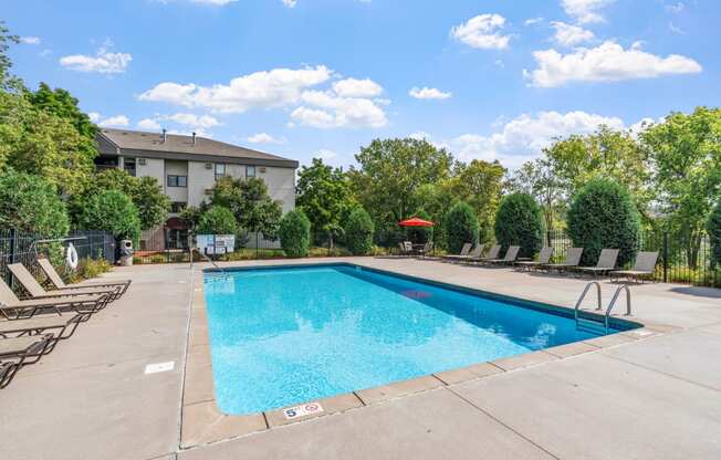 a swimming pool with chairs and a building in the background