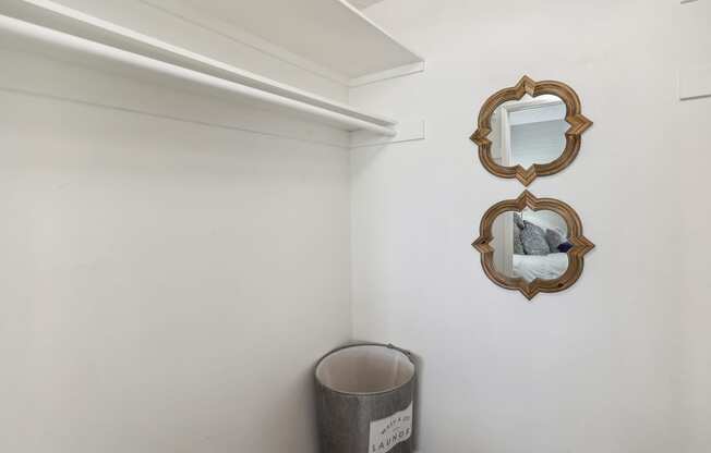 a white room with two mirrors on the wall and a trash can