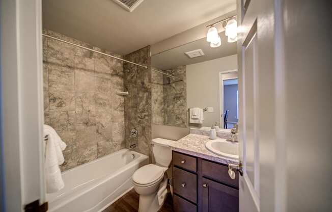 Tiled Bathroom with Tub and Dark Cabinets