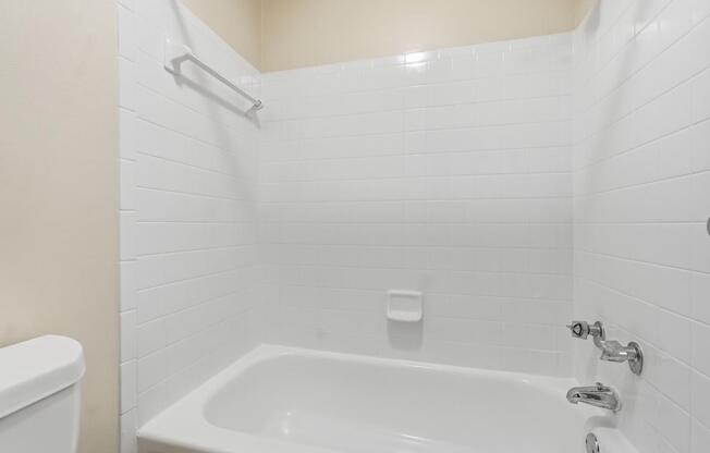 A white bathroom with a tub and toilet.