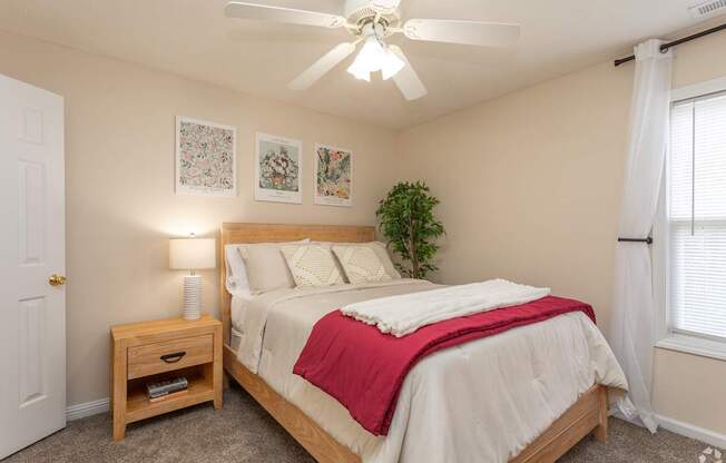 A bedroom with a bed, nightstand, and a ceiling fan.