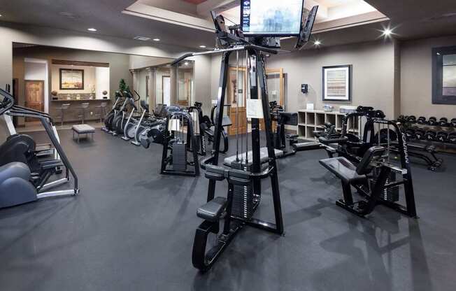 A gym with a variety of exercise equipment including treadmills, stationary bikes, and weight machines.
