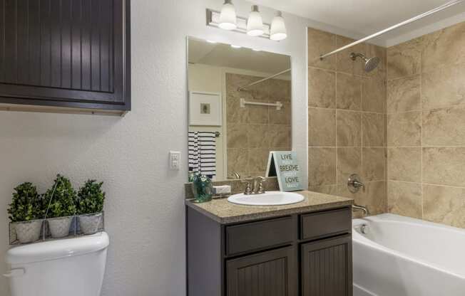 bathroom with granite-style counters, and tile shower surround
