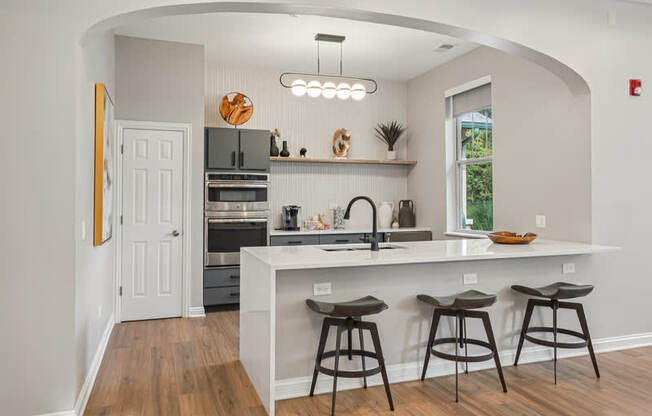A kitchen with a white countertop and bar stools.