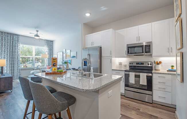 a kitchen with white cabinets and a marble counter top