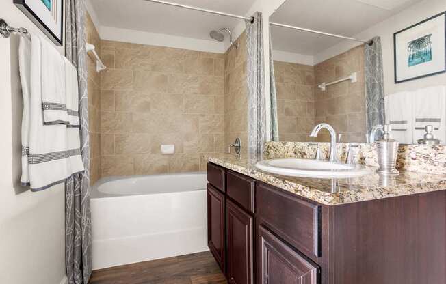 A bathroom with a white tub and a sink with a marble counter.