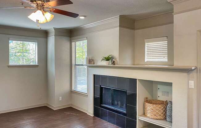 Living room in the 1486-square-foot 3-bedroom, 3-bath apartment with attached 2-car garage at The Brownstones in Far North Dallas, Texas, featuring a fireplace with an extended mantel ledge and built-in storage niche.