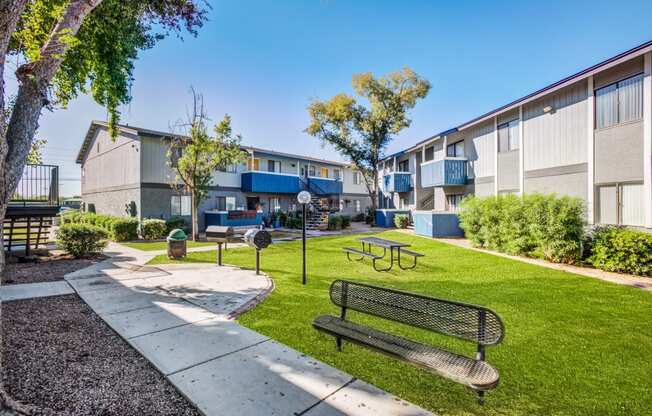 a park with a bench and picnic table in front of a building