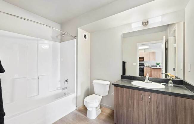 A bathroom with a toilet, sink, and mirror.