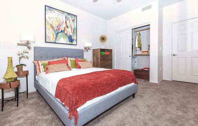 Queen sized Platform bed decorated with bright trendy throw pillows in large bedroom in 1x1 model apartment