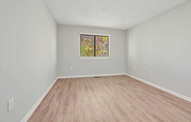 A room with a window and wooden flooring.