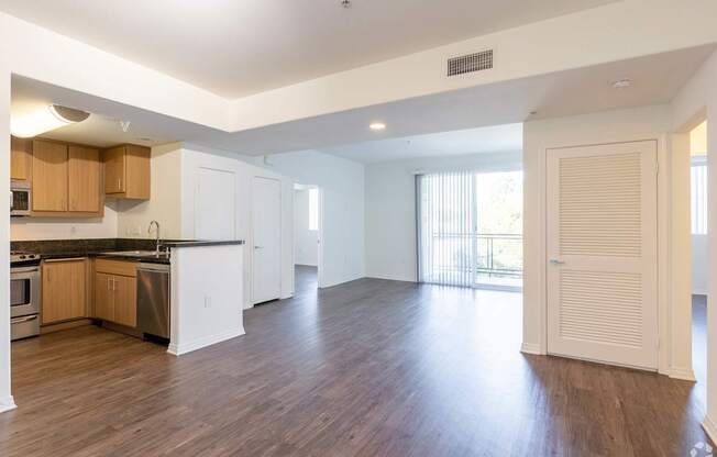 A spacious kitchen with wooden floors and white cabinets.