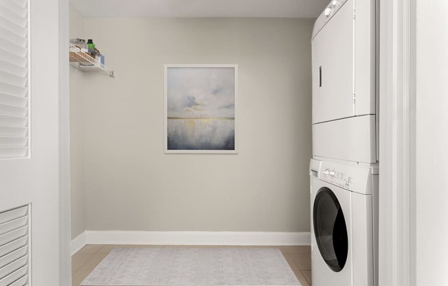 A laundry room with a washing machine and a painting on the wall.