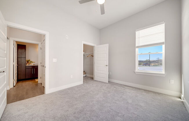 an empty living room with a ceiling fan and a door to a bathroom