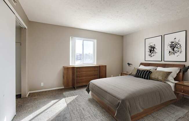 A bedroom with a bed, nightstand, and two framed pictures on the wall. Omaha, NE Evergreen Terrace Apartments