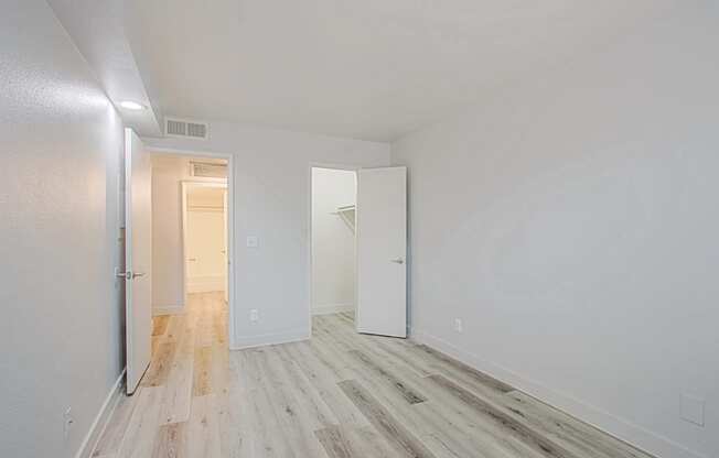 a bedroom with hardwood floors and white walls