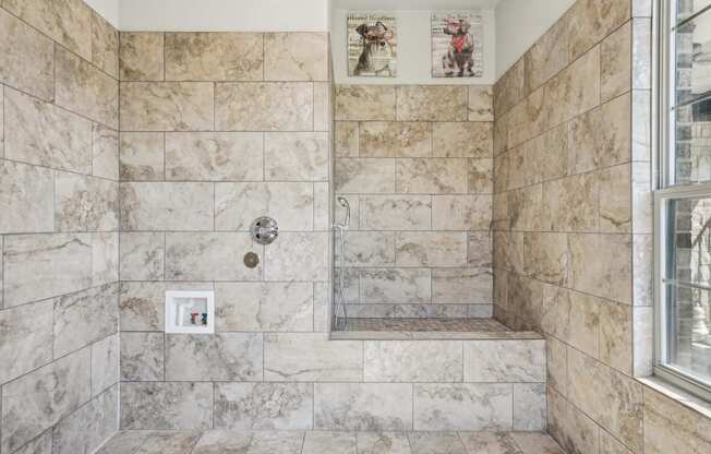 A bathroom with a marble tile wall and a small picture frame on the wall.