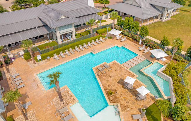 an aerial view of a resort style pool with lounge chairs and umbrellas