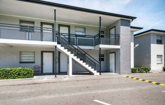 an exterior view of a building with stairs and a parking lot