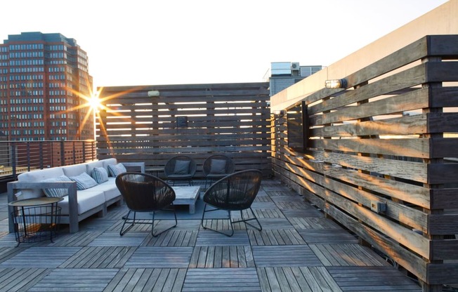 a roof deck with furniture and a building in the background