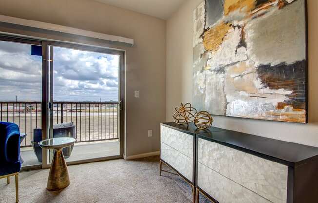 a living room with a large painting on the wall and a glass door leading to a balcony