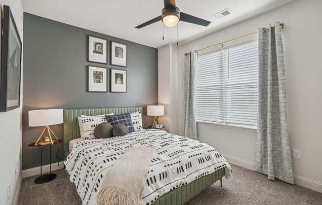 A bedroom with a bed, two lamps, and a ceiling fan.