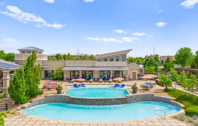 a swimming pool with chairs around it in front of a hotel