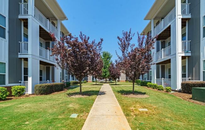 an apartment building with grass and trees in front of it