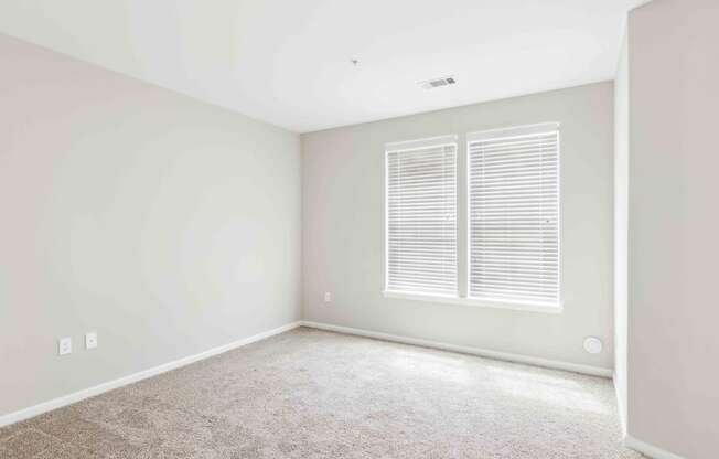 a bedroom with white walls and a window with white shutters at West 130, West Hempstead