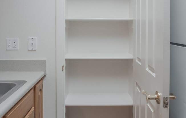 an empty kitchen with white shelves and a refrigerator