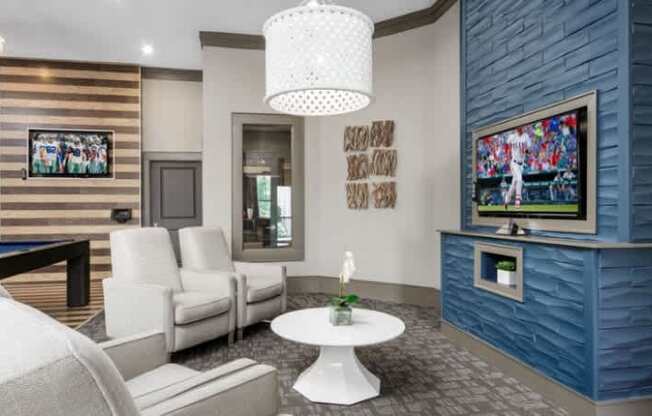 A living room with a white sofa set, a TV, and a pool table.