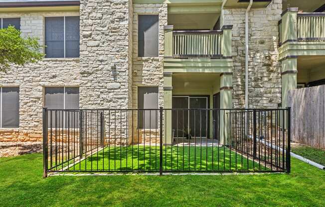 an apartment building with a yard behind a iron fence