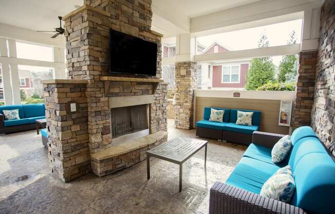 the living room has a large stone fireplace and blue couches
