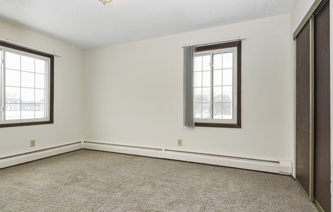 a bedroom with two windows and a carpet. Fridley, MN Georgetown on the River Apartments