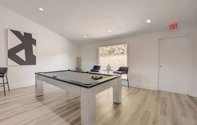 A pool table in a room with a chair and a painting.